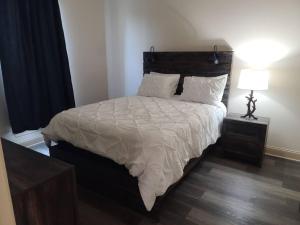 a bedroom with a large bed with white sheets and a lamp at Villa 5 in Hammond
