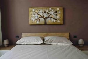 un quadro di un albero sopra un letto con due cuscini di La Terra del Mare a La Spezia