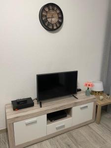 a flat screen tv on a wooden entertainment center with a clock at Appartement de charme à 2 min de la plage in Vallauris