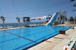 a swimming pool with a slide in front of the ocean at Almog Tower in Haifa