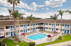 an apartment building with a swimming pool and palm trees at Motel 6-Pismo Beach, CA in Pismo Beach