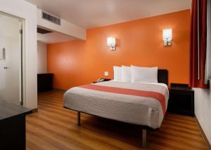 Motel 6-Pismo Beach, CA في شاطئ بيسمو: سرير كبير في غرفة بجدار برتقالي