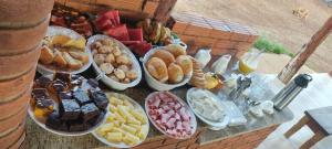 a table full of different types of pastries and desserts at Pousada Chalés Praia Vermelha in São João Batista do Glória