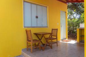 a table and chairs in a room with a yellow wall at Pousada Chalés Praia Vermelha in São João Batista do Glória