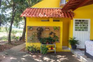 a small yellow house with a red roof at Pousada Chalés Praia Vermelha in São João Batista do Glória