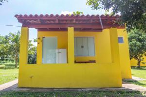 a yellow house with a red roof at Pousada Chalés Praia Vermelha in São João Batista do Glória
