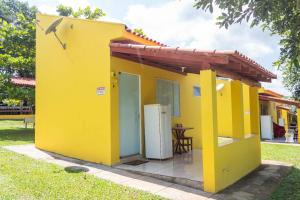 a small yellow house with a table in a yard at Pousada Chalés Praia Vermelha in São João Batista do Glória