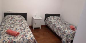 two beds in a small room with a night stand at Apartamentos Plaza Mayor in León