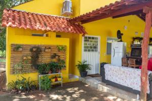 a yellow house with a kitchen and a refrigerator at Pousada Chalés Praia Vermelha in São João Batista do Glória