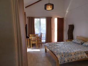 a bedroom with a bed and a table and a chair at SASCHAS PLACE in Siquijor