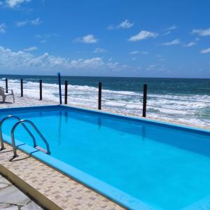 a swimming pool with the beach in the background at Casa em condomínio, beira mar e piscina Barra de São Miguel - Maceió- AL in Barra de São Miguel