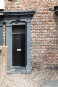 a door to a brick building with a black door at Stockton town centre studio apartments free parking and Wi-Fi in Stockton-on-Tees