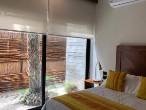 a bedroom with a bed and a large window at La Casa de María 11:11 in Chemuyil