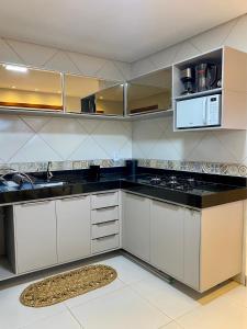 a kitchen with white cabinets and a black counter top at Acoara PRAIA in Jericoacoara