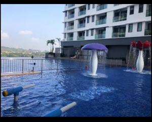 a swimming pool with an umbrella in the water at EasyOne Homestay@Vista Bangi in Kajang