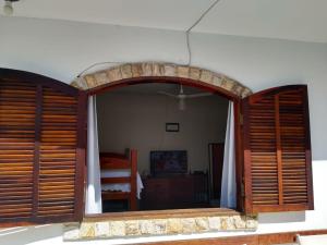 Zimmer mit einem großen Fenster mit Fensterläden aus Holz in der Unterkunft Cabo Frio Suíte com cozinha in Cabo Frio