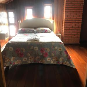 a bedroom with a bed with a floral bedspread at Casarão Villa maggi in Canela +9 photos
