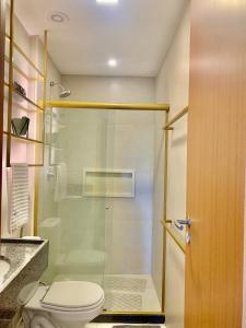 uma casa de banho com um WC e uma cabina de duche em vidro. em Apartamento família com 3 quartos no Eco Resort Carneiros em Tamandaré