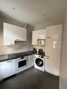 a kitchen with white cabinets and a washing machine at Elegant appartement Trocadéro in Paris