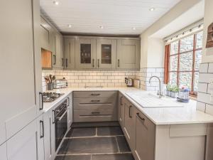 eine Küche mit weißen Schränken und einer Spüle in der Unterkunft Tanner Croft Cottage in Ambleside