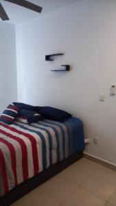 a bed with a red white and blue striped blanket at Beach Castell Suites in Playa del Carmen