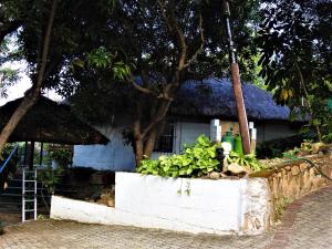 a small white house with a grass roof at Impala Niezel Lodge & Guest House in Hazyview