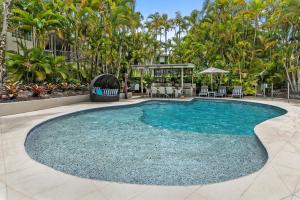 a swimming pool with blue water and palm trees at Penthouse with Private Roof top terrace- NOOSA in Noosa Heads