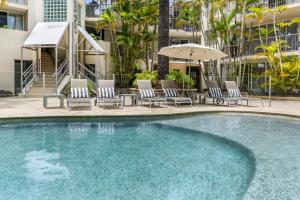 a swimming pool with chairs and an umbrella at Penthouse with Private Roof top terrace- NOOSA in Noosa Heads