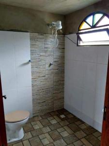 a bathroom with a toilet and a window at Chalé Roots in São Thomé das Letras