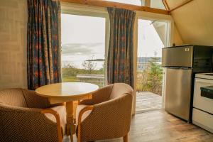a kitchen with a table and chairs and a refrigerator at Glenghorm Beach Resort in Ingonish