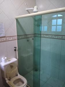 La salle de bains est pourvue de toilettes et d'une douche en verre. dans l'établissement Cabo Frio Suíte com cozinha, à Cabo Frio