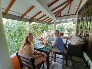 Um homem e uma mulher sentados numa mesa no alpendre. em Sadee's Place em Dambulla