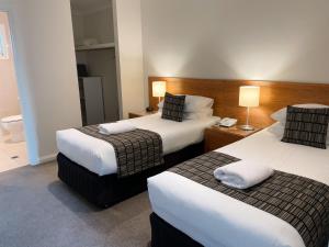 una habitación de hotel con 2 camas y una lámpara en Red Earth Motel en Broken Hill