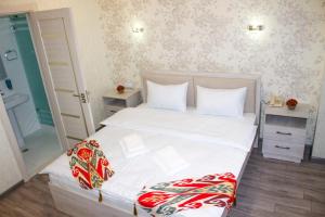 um quarto com uma cama grande com lençóis brancos e almofadas em Hotel Taht em Tashkent