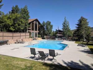 a swimming pool with chairs and a house at Cozy Top Floor Condo with Mountain Views in Park City