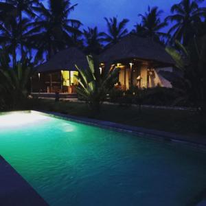 a swimming pool in front of a house at night at Taman Bintang Villa Ubud in Ubud