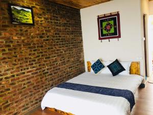 two beds in a room with a brick wall at Mintu Home in Sapa