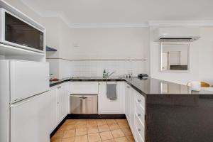 a kitchen with white cabinets and a black counter top at Calypso Plaza Resort Unit 429 in Gold Coast +3 photos
