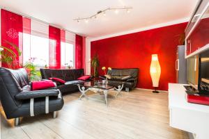 una sala de estar con paredes rojas y muebles de cuero negro. en Ferienwohnung Köln Messenähe en Colonia