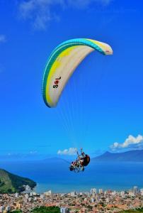 a person flying through the air with a parachute at Pousada Caraguá in Caraguatatuba