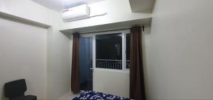 a bedroom with a window and a bed and a chair at 05-06 at Wind Residences Tagaytay in Tagaytay