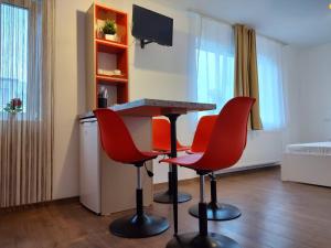 ein Wohnzimmer mit einem Tisch und 4 roten Stühlen in der Unterkunft GARSONIERA DANIA&PETRU in Târgu Ocna