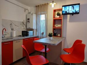 eine Küche mit roten Stühlen und einem Tisch mit einem TV in der Unterkunft GARSONIERA DANIA&PETRU in Târgu Ocna
