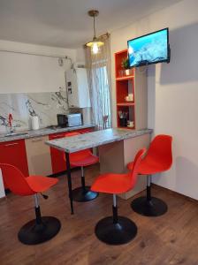 eine Küche mit einem Tisch und 2 roten Stühlen in der Unterkunft GARSONIERA DANIA&PETRU in Târgu Ocna