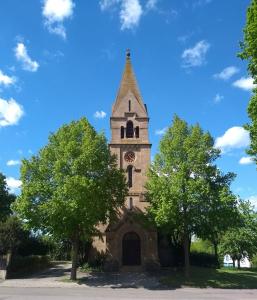 eine Kirche mit einem Turm mit einer Uhr drauf in der Unterkunft Gasthaus Linde in Ingelfingen