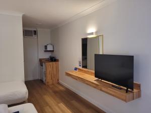 a flat screen tv sitting on top of a wooden stand at SureStay Hotel by Best Western The Clarence on Melville in Albany