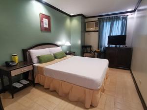 um quarto com uma cama grande e uma televisão em Tagaytay Country Hotel em Tagaytay