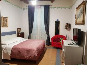 a bedroom with a bed and a red chair at B&B Casa San Jacopo al Giardino in Lucca