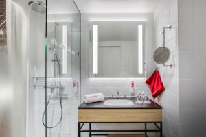 a bathroom with a sink and a shower with a mirror at IntercityHotel Dortmund in Dortmund