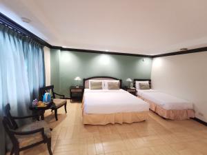 um quarto com 2 camas, uma mesa e uma cadeira em Tagaytay Country Hotel em Tagaytay